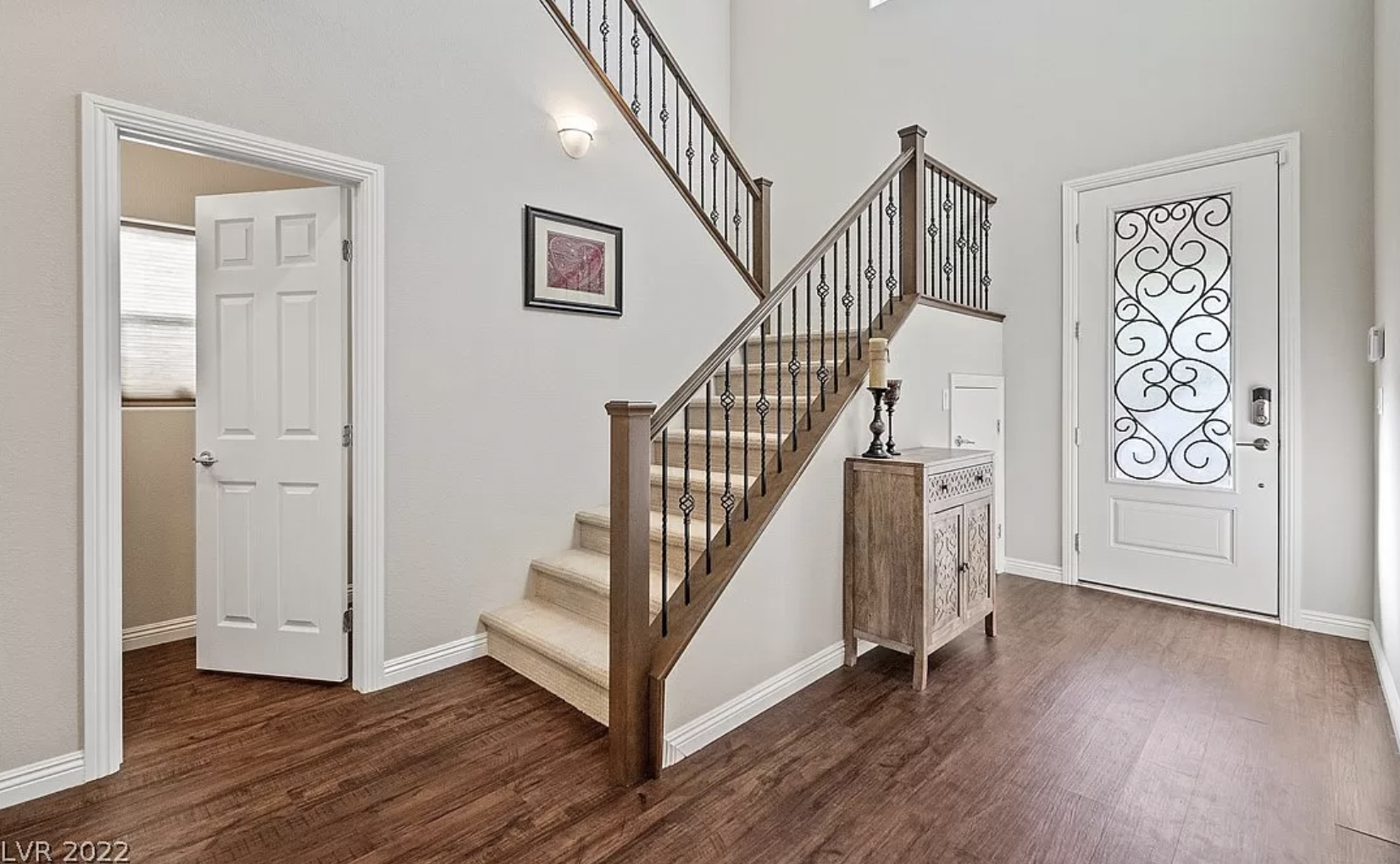 A front entrance featuring an ornate staircase, high ceilings, and wood-toned floor